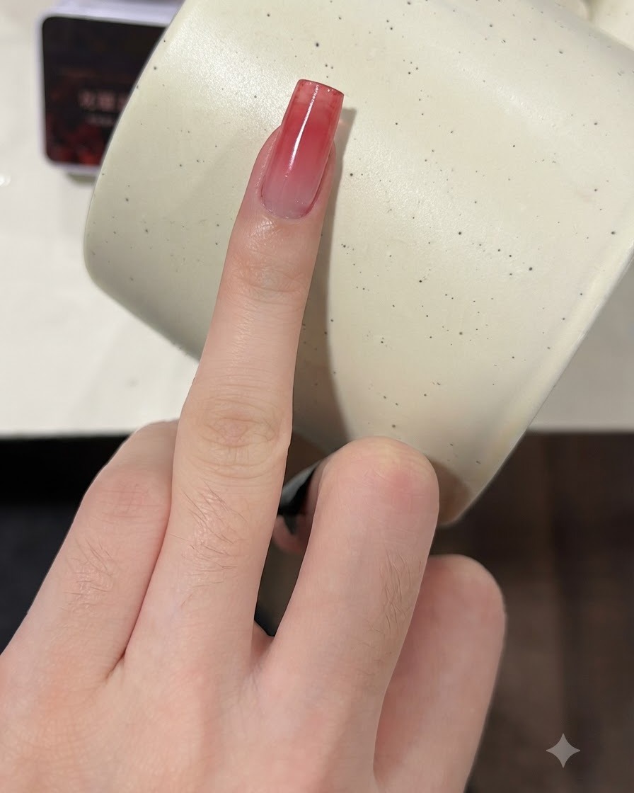 Un dito con ununghia dalla sfumatura rosso vino in crescita che viene premuta con una spugnetta per una seconda mano.