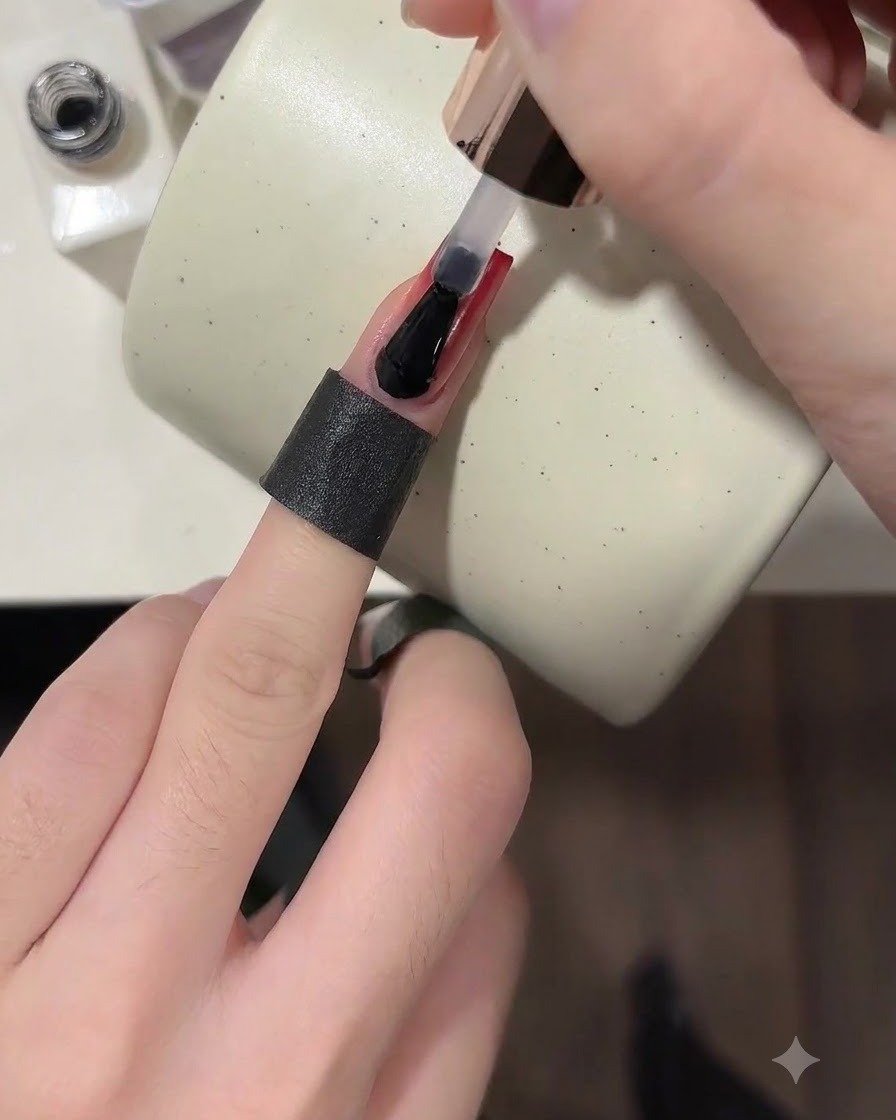 Un pennello che applica un top coat lucido trasparente su ununghia completata con sfumatura rosso vino.