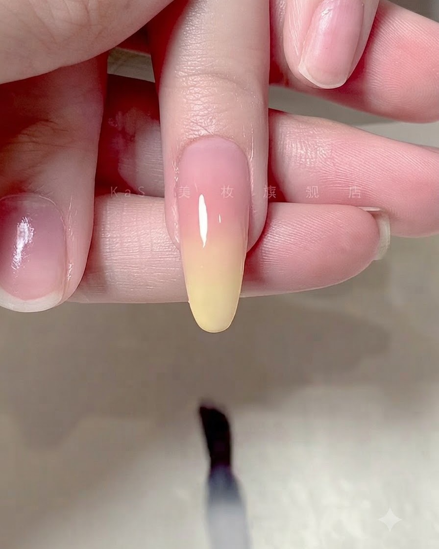 Un pennello che applica un top coat trasparente e lucido su un design di unghie con sfumatura ombré.