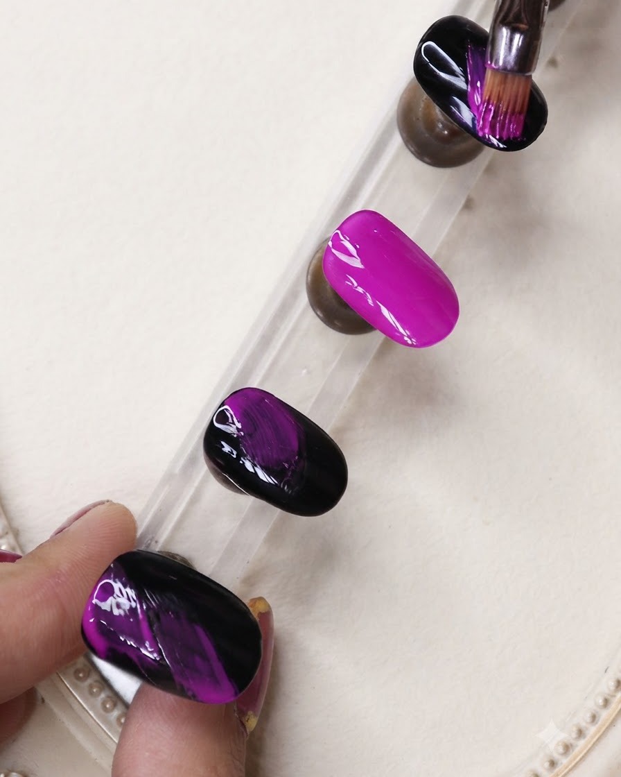 Un pennello a punta fine applica strisce di gel nero su ununghia viola neon vibrante posizionata su un supporto da esposizione.
