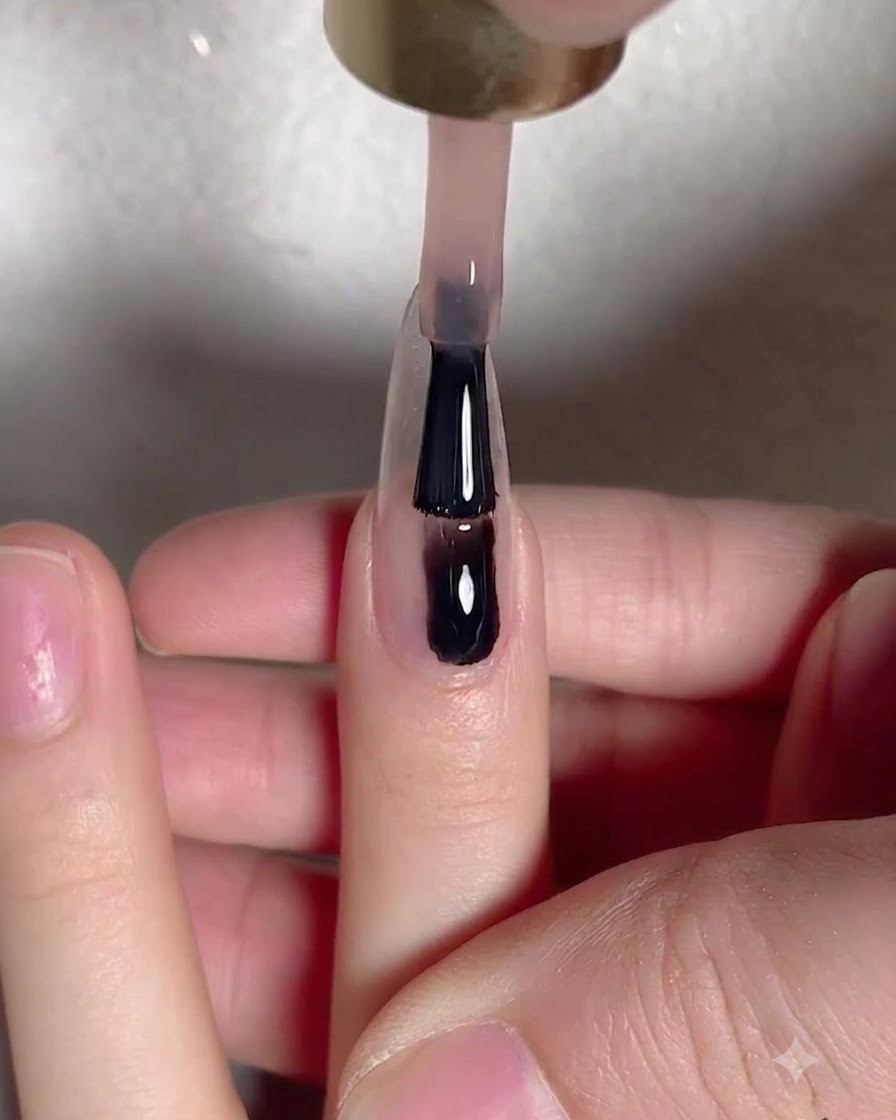 Un pennello da gel applica uno strato uniforme di base nude al centro di ununghia naturale allungata.