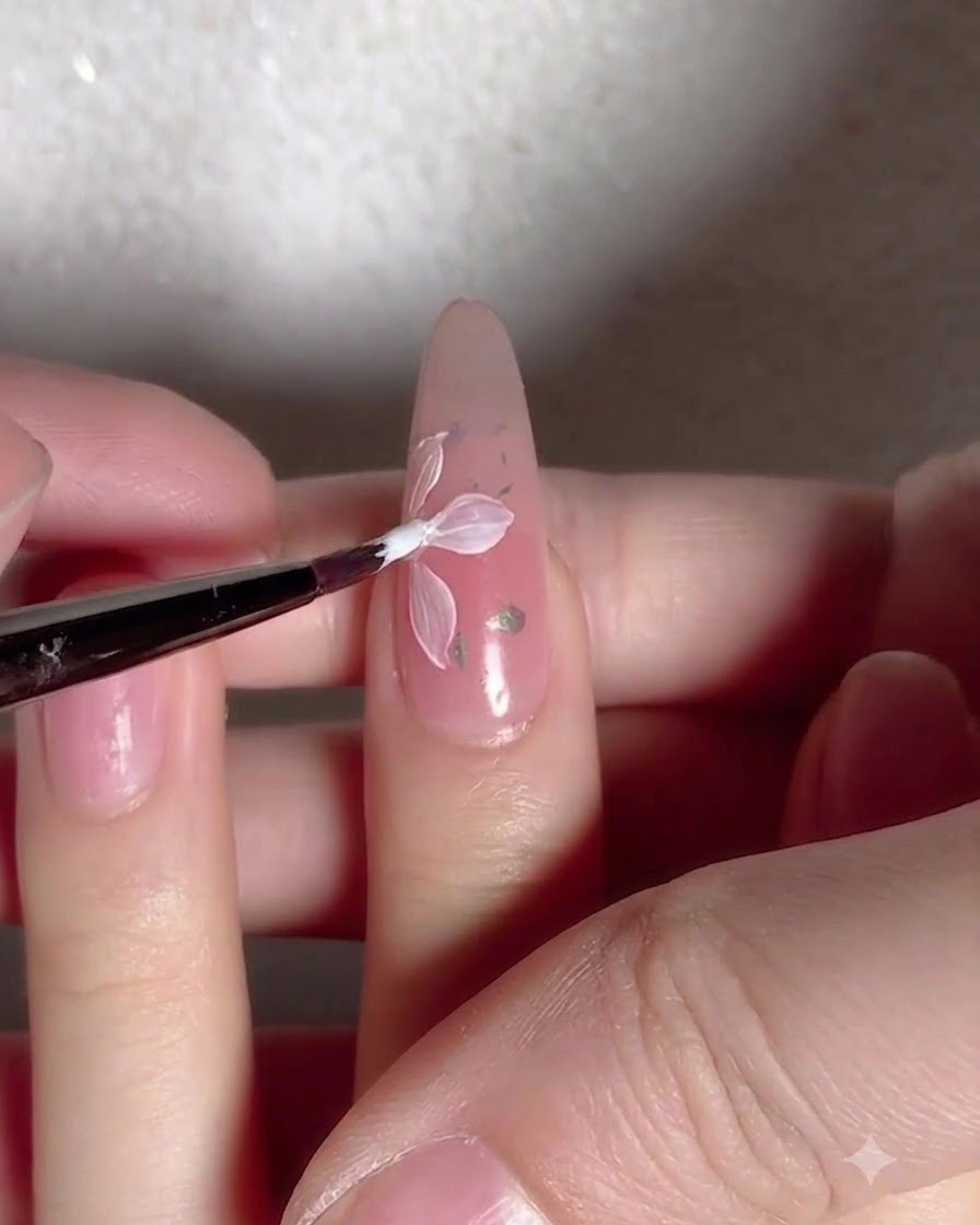 Un pennello applica uno strato di top coat lucido trasparente su ununghia decorata con fiori e fiocchi.