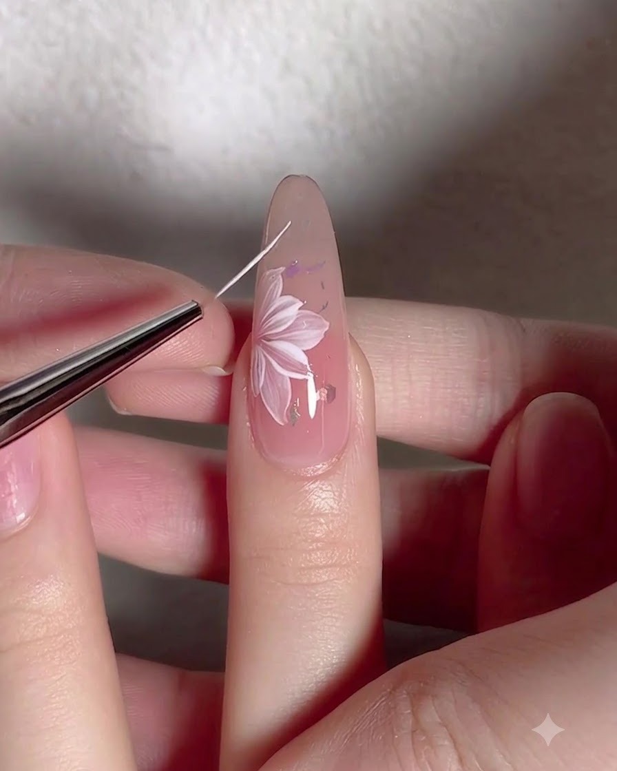 Un pennello liner sottile disegna delicate linee di tralci bianchi attorno a un fiore dipinto su ununghia.