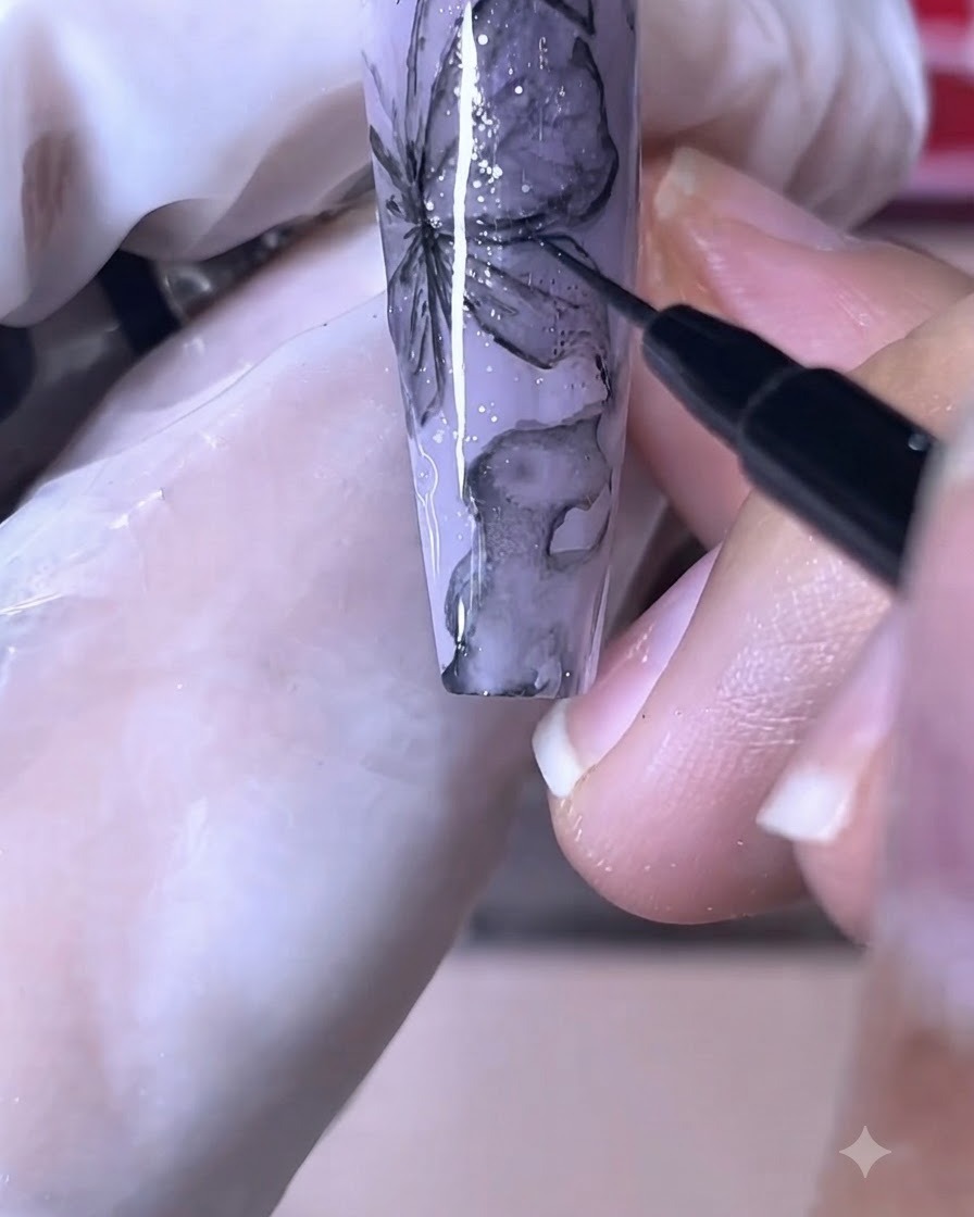 Un pennello fine per unghie che disegna linee nere nitide su un design a farfalla viola.