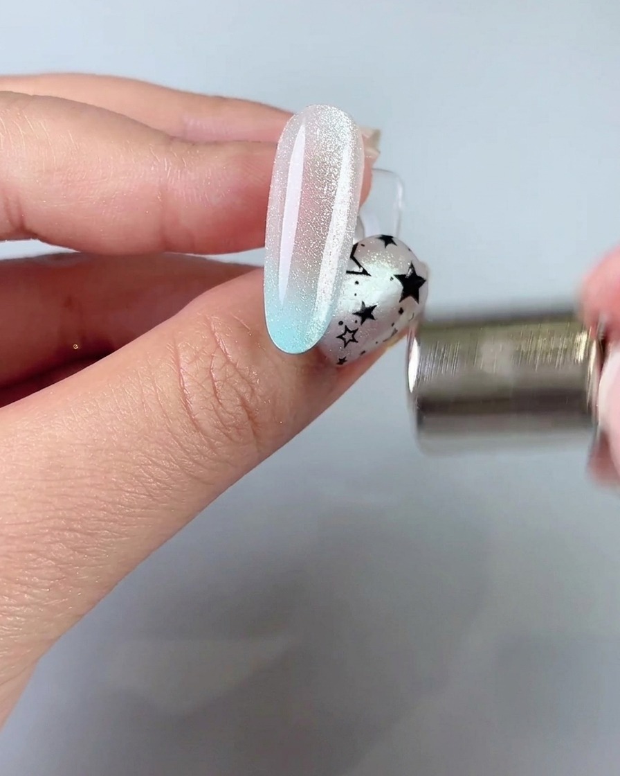 Una bacchetta magnetica tenuta vicino al lato di ununghia per tirare e modellare unampia fascia di luce cat eye.