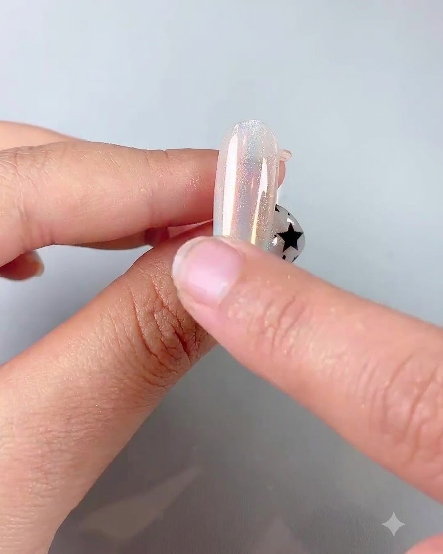 Un dito che usa un applicatore in spugna di silicone per strofinare la polvere cromata iridescente su ununghia lucida.