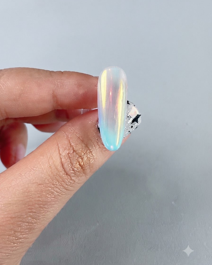 Un primo piano di unghia finita in cromo aurora iridescente che mostra un vibrante riflesso a specchio multicolore.