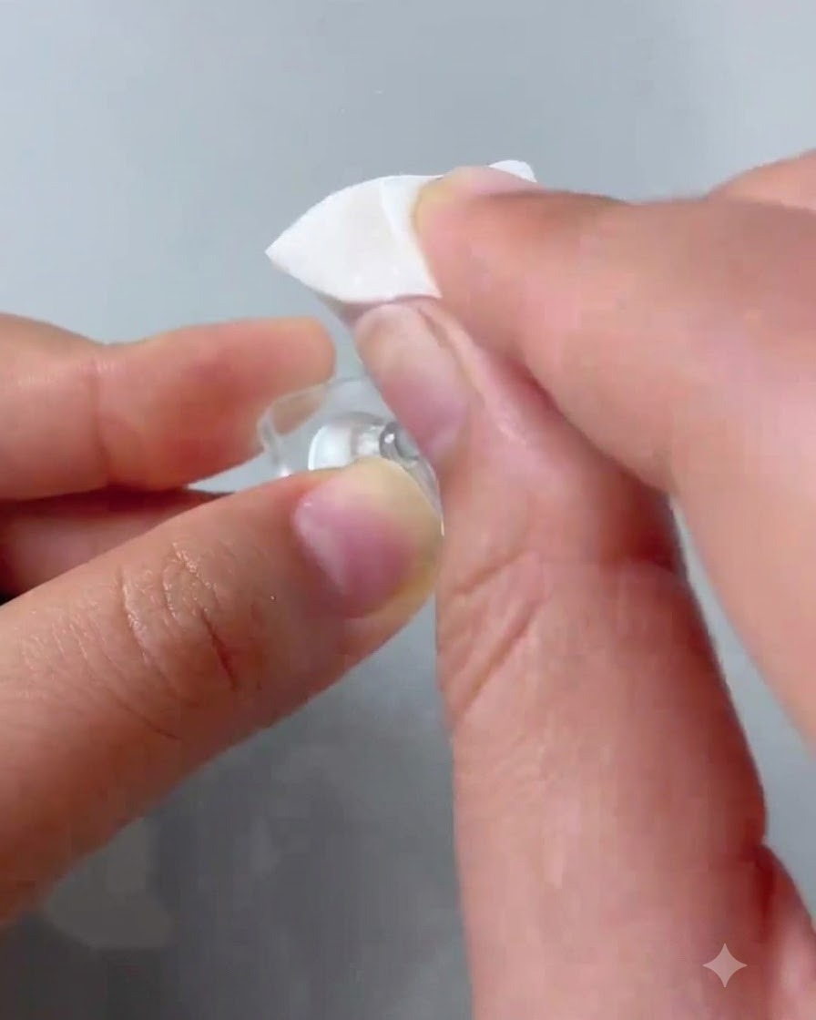 Un applicatore in spugna che tampona lo smalto gel rosa sulla punta di ununghia di prova trasparente.
