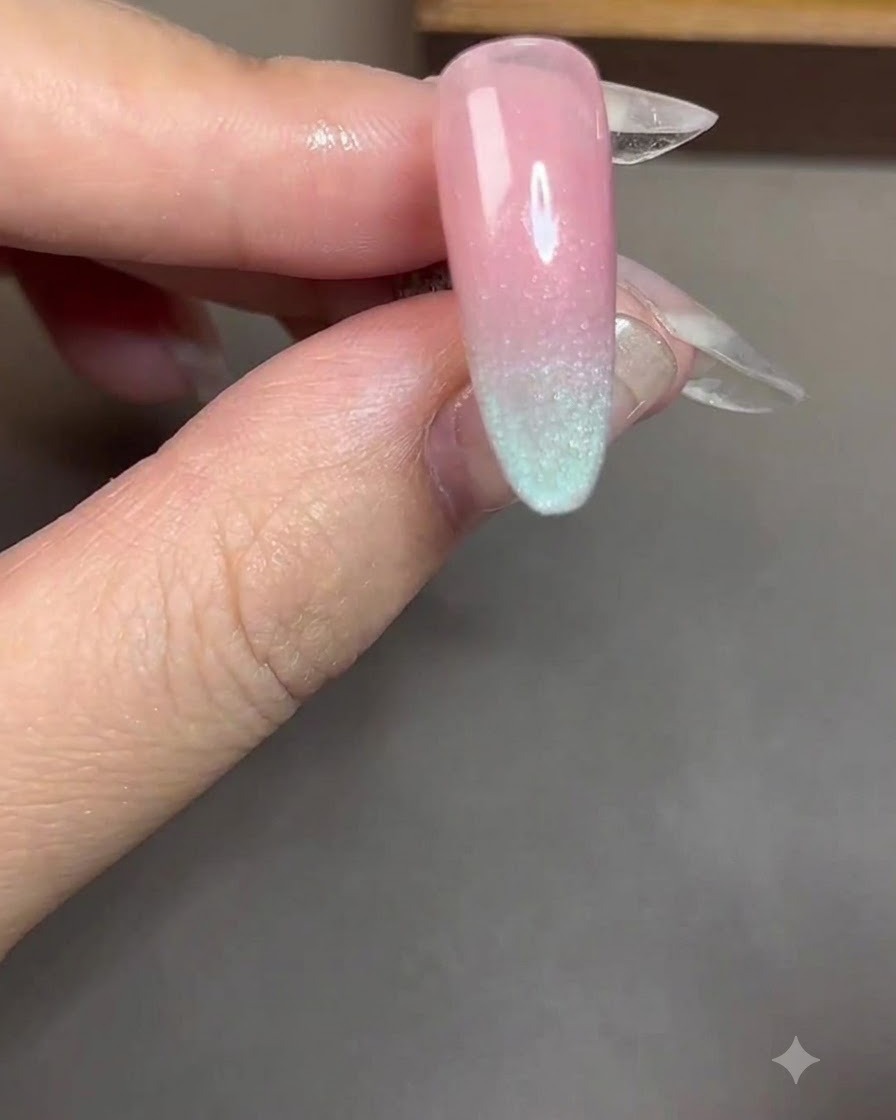 Un magnete cilindrico tenuto vicino e parallelo a ununghia rivestita di gel cat-eye blu.