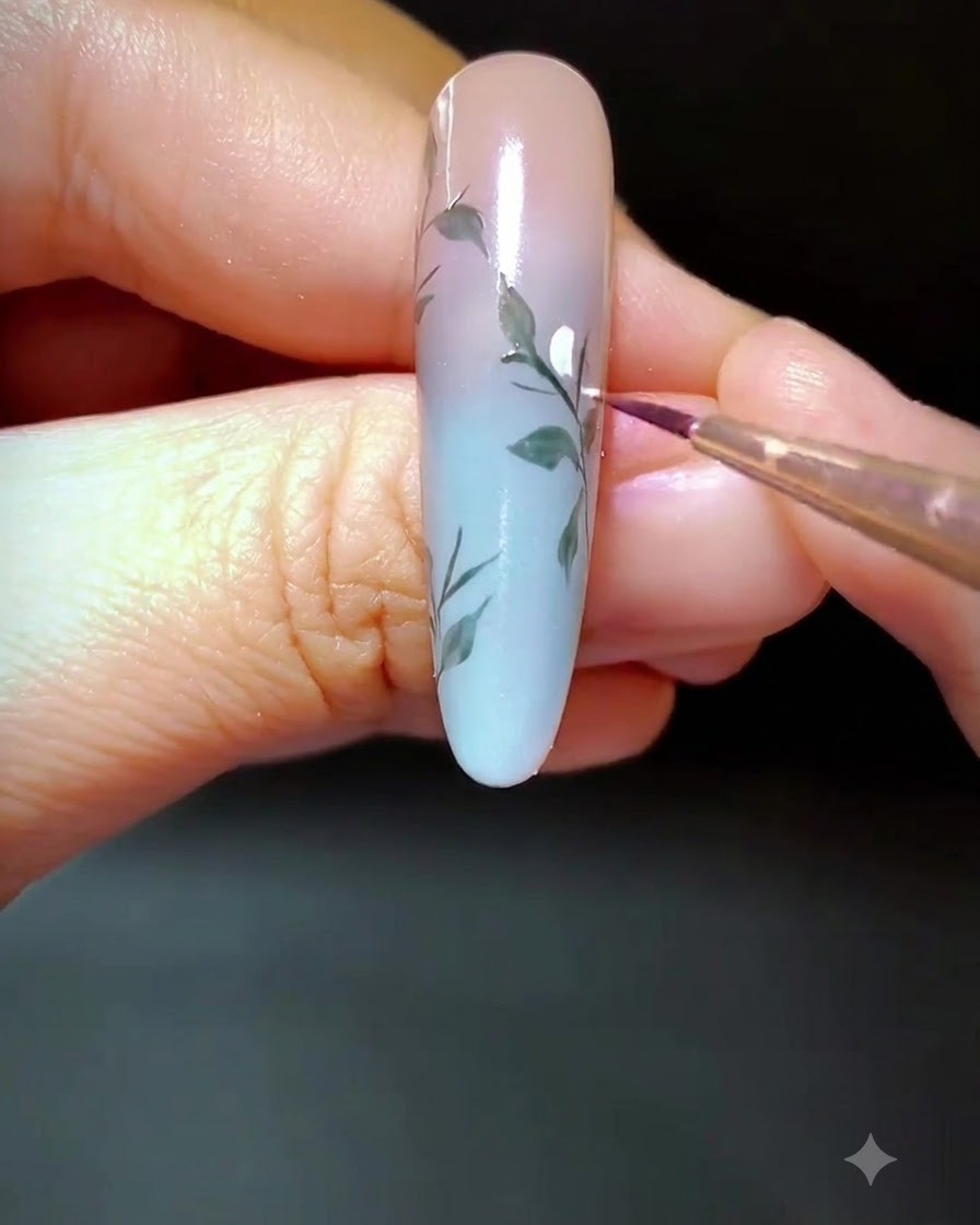 Un primo piano di ununghia decorata in cui vengono applicati piccoli punti di gel bianco lungo il ramo dipinto.