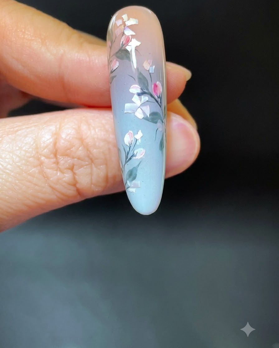 Una mano con nail art floreale in conchiglia finita inserita allinterno di una lampada di polimerizzazione UV/LED bianca.