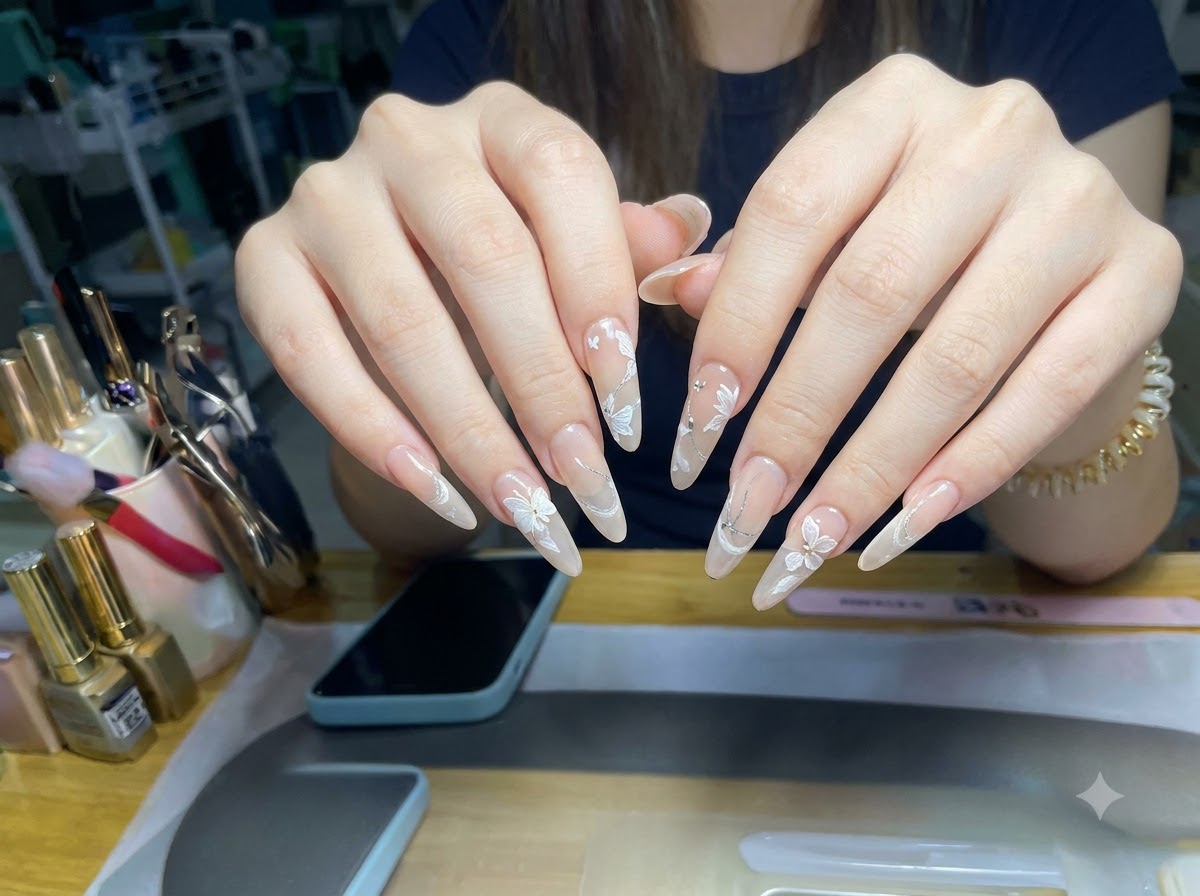 Unangolazione incentrata sulla macro che mostra lo strato glitter cat-eye e i design floreali 3D su unghie a forma di mandorla.