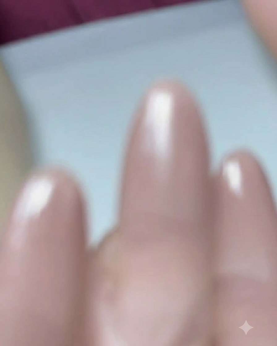 Un primo piano di un pennello per unghie che applica il gel base coat su ununghia preppata a forma a mandorla.