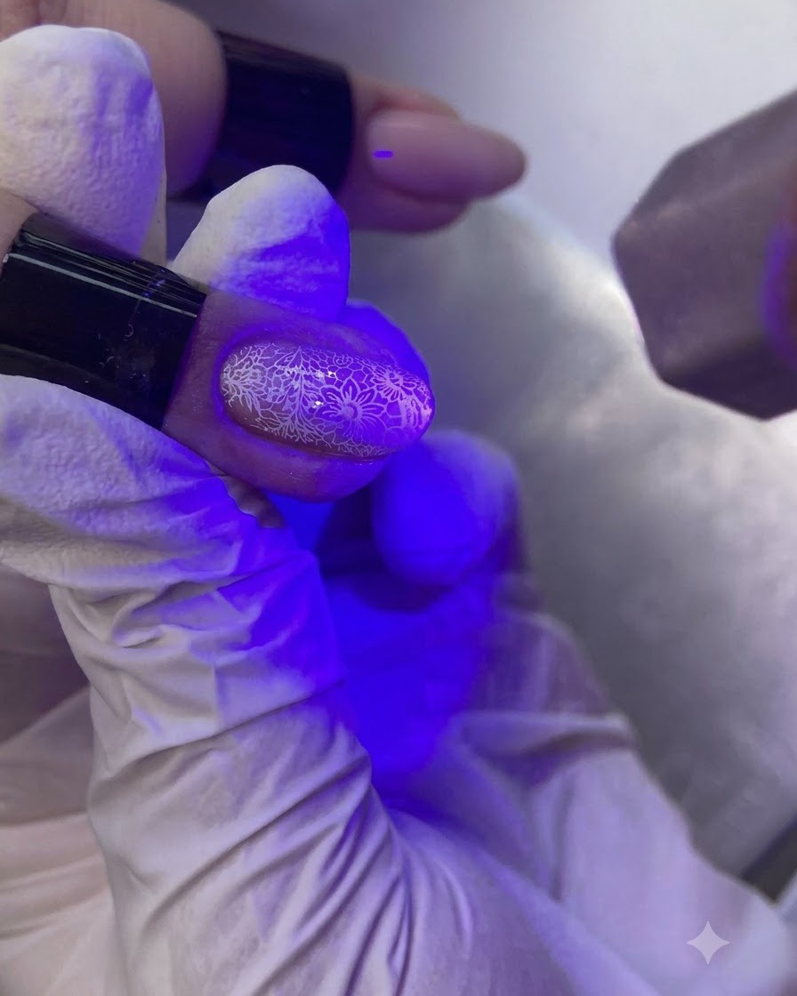 Una mano sotto una lampada UV/LED per unghie che polimerizza ununghia decorata.