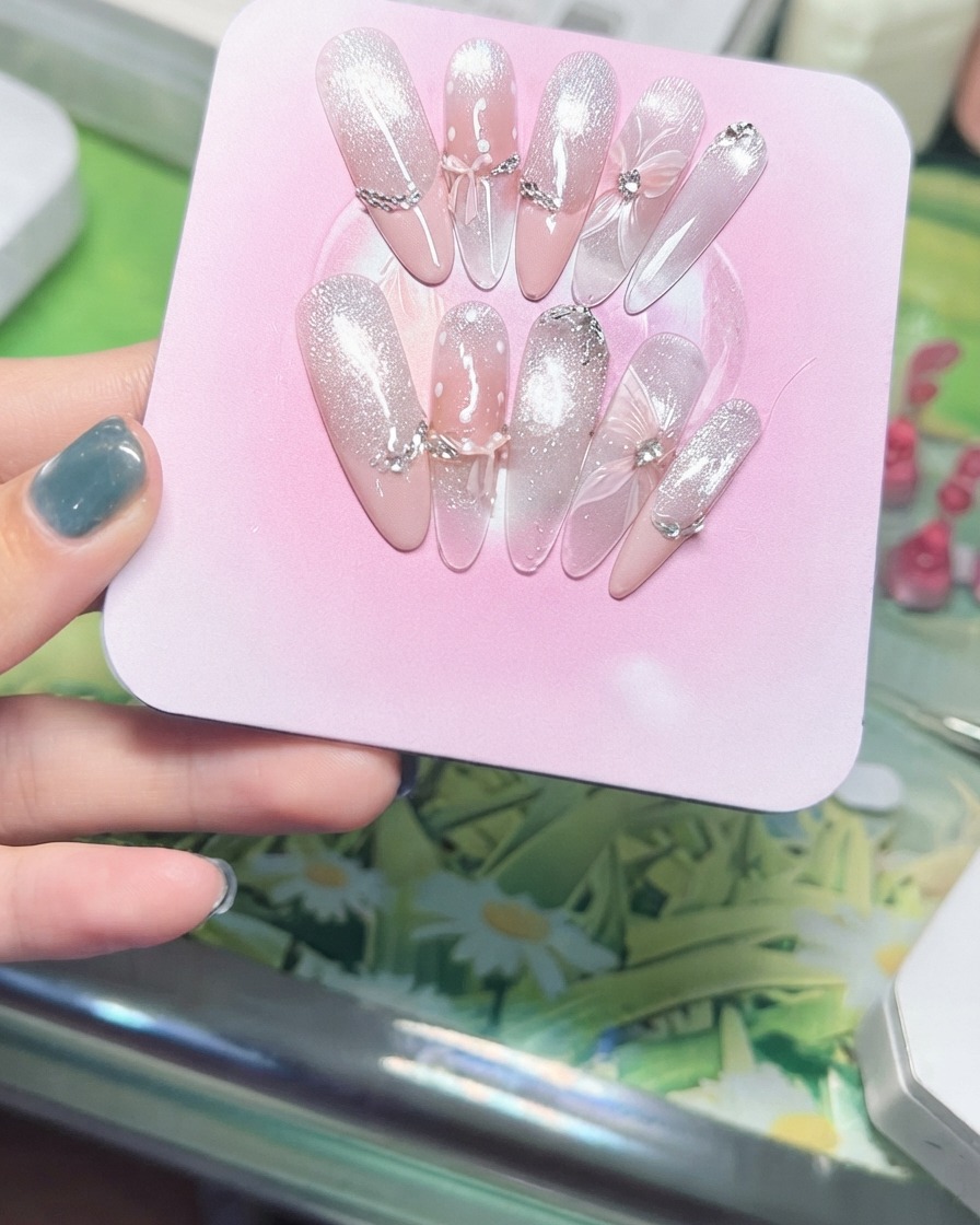 Una mano che inclina un espositore rosa per mostrare le particelle scintillanti del cat eye magnetico che catturano la luce.