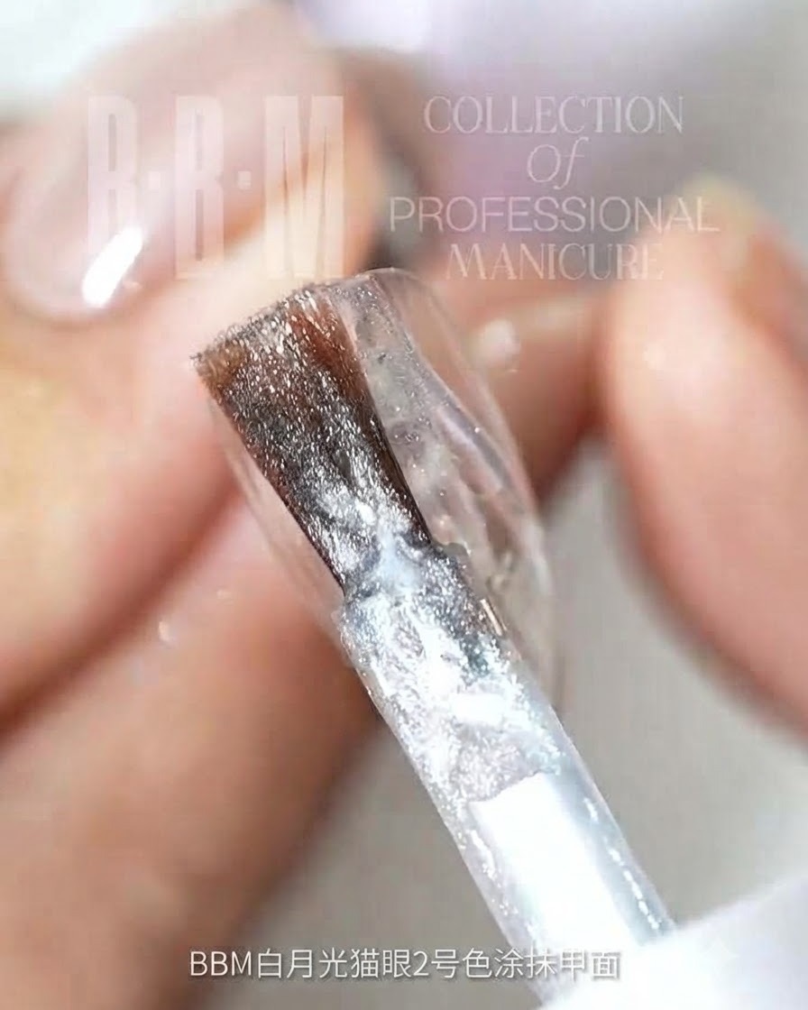 Un pennello da unghie applica il gel cat-eye glitterato argentato su una superficie trasparente dellunghia.