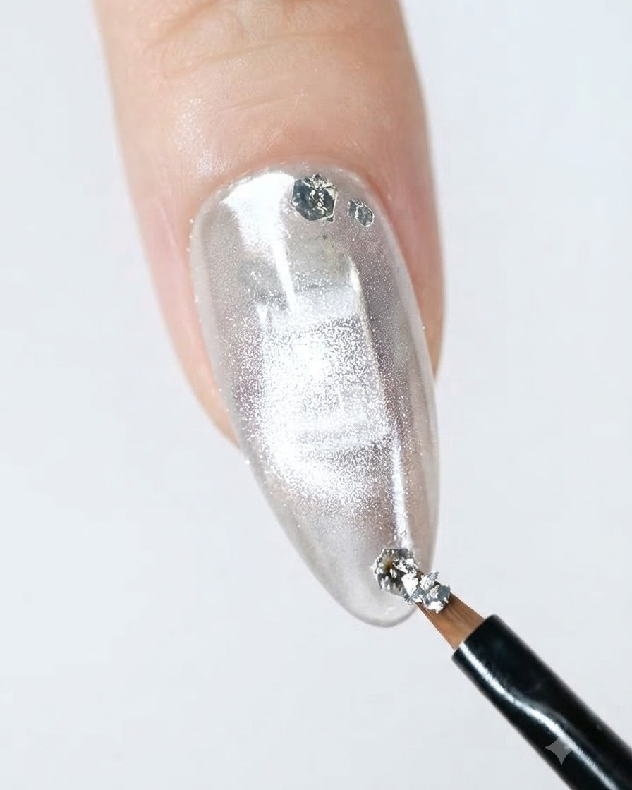 Un pennello liner sottile applica scaglie di glitter argentato sul bordo di ununghia finita.
