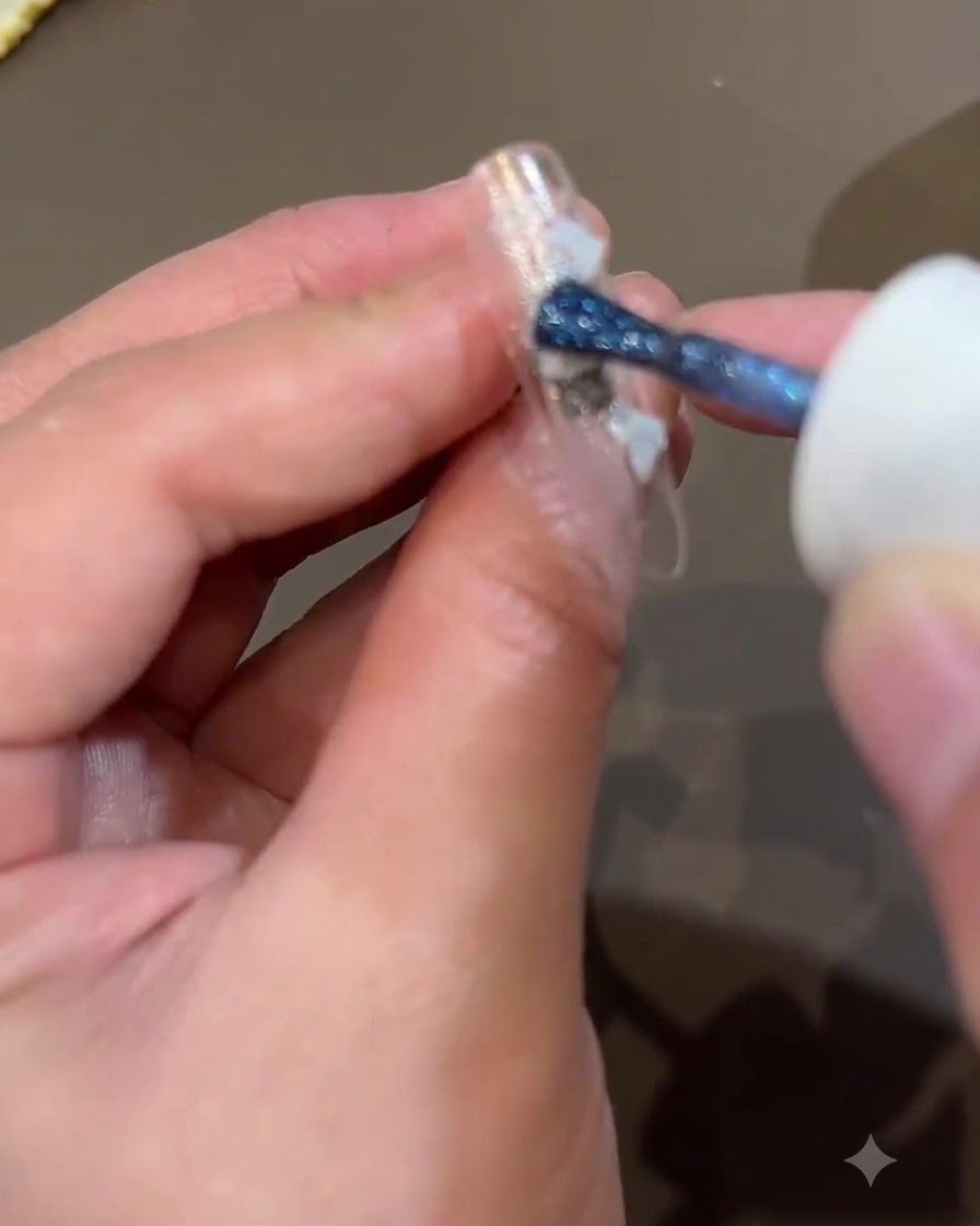 Un pennello applica lo shimmer blu scuro sulla superficie dellunghia per aggiungere profondità al design.