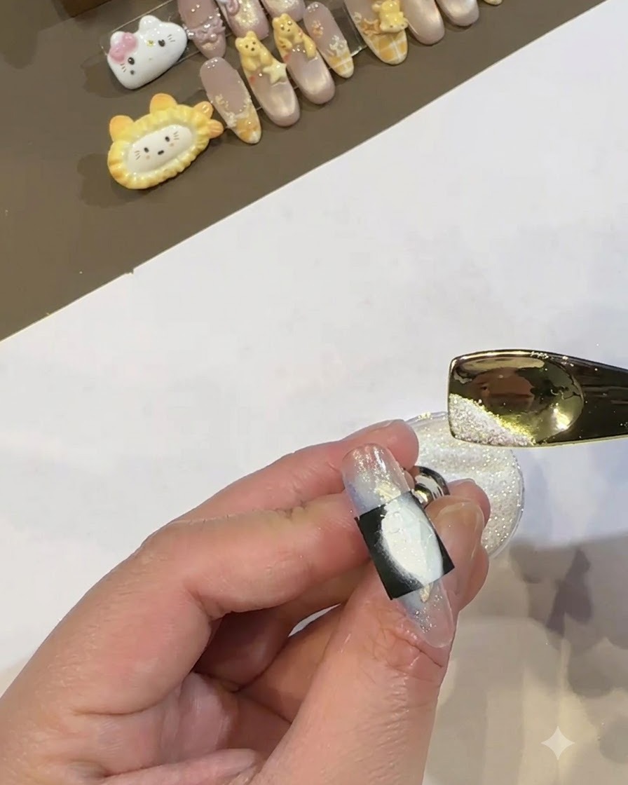 Un piccolo cucchiaio di metallo versa polvere bianca scintillante sullarea di gel bianco bagnato incorniciata da uno stencil nero su ununghia.