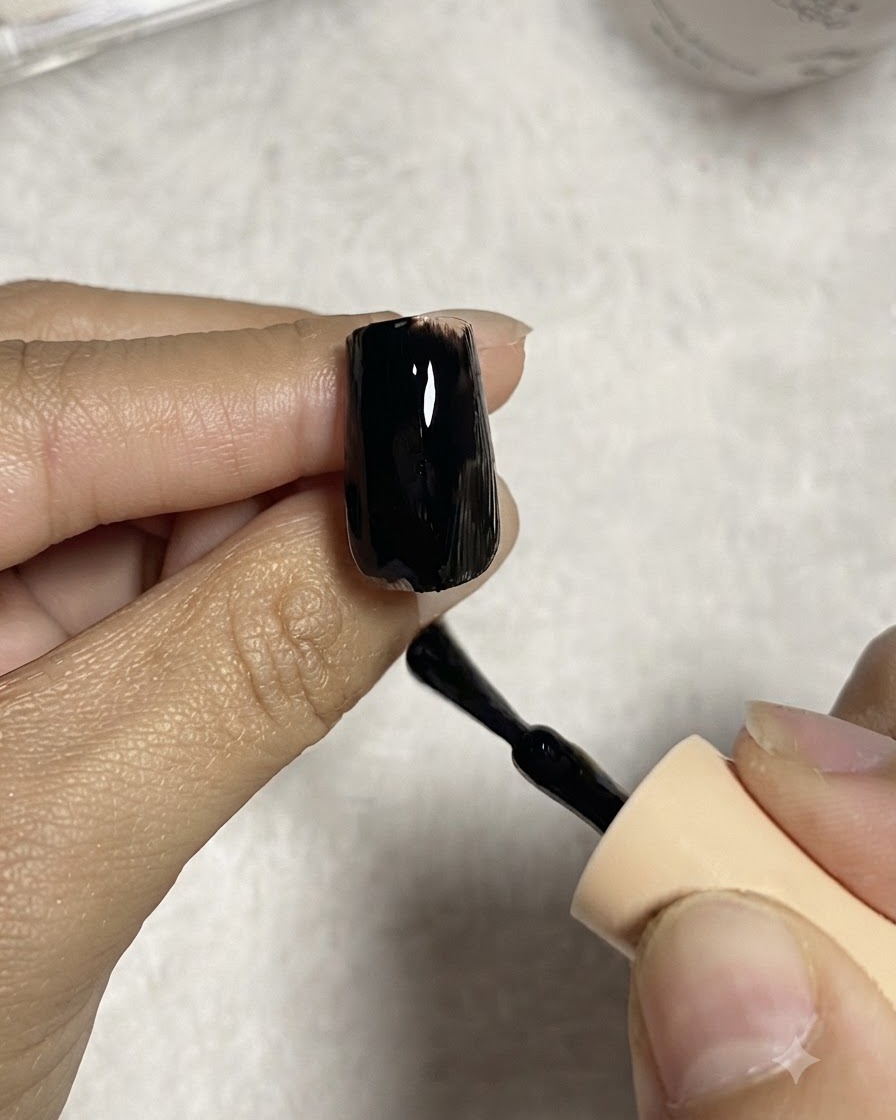 Pennello per unghie che applica uno strato uniforme di smalto gel nero su una tip trasparente per allungamento.