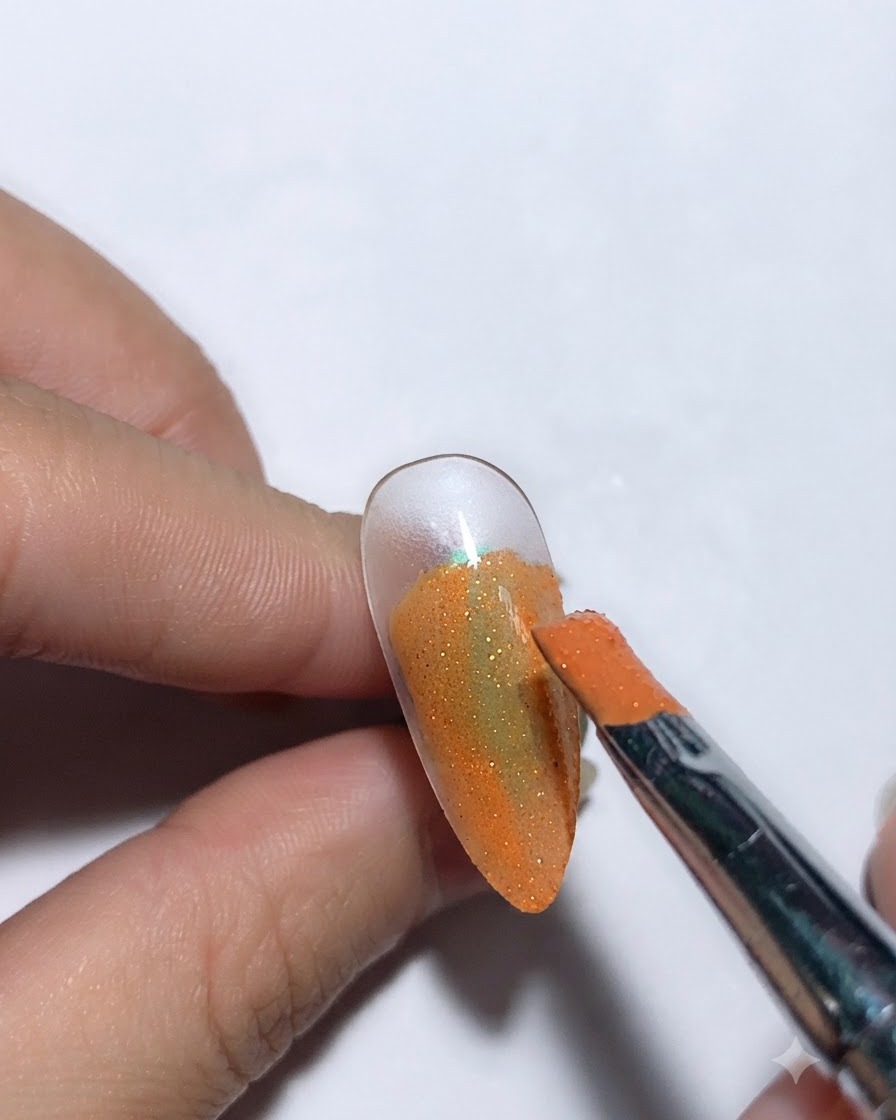 Un pennello che applica la colla per cielo stellato su una base per unghie di colore arancione.