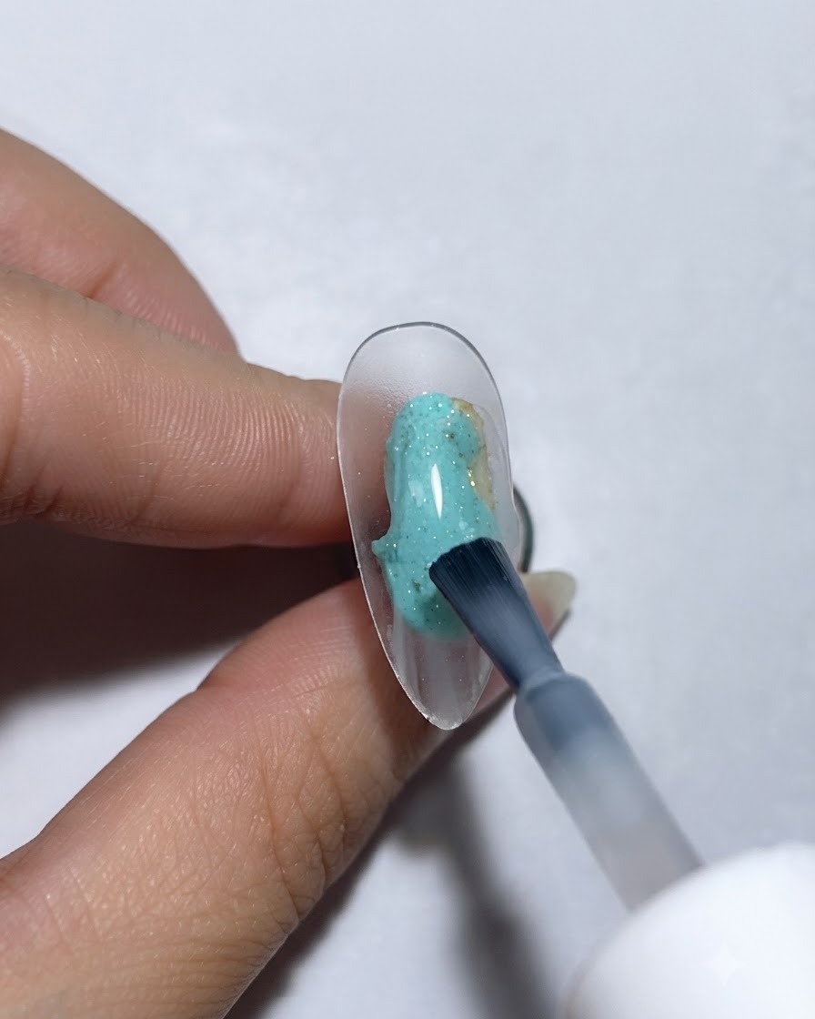 Un pennello che applica la base in gel proteico su ununghia trasparente da esposizione.