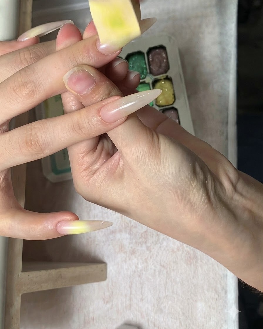 Primo piano di una spugnetta che tampona delicatamente il colore sulla superficie dellunghia sfumata.