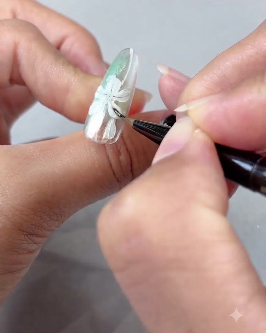 Un pennello per unghie che sfuma delicatamente lombreggiatura in gel ambra sui petali di giglio dipinti di bianco.