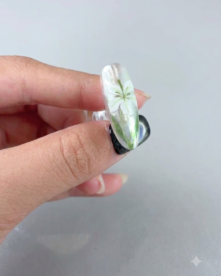 Ununghia completata che mostra un design a giglio bianco sotto un top coat sigillante effetto velluto opaco.