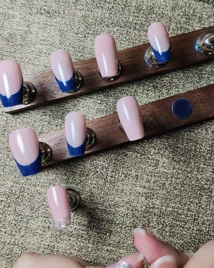 Uno strumento che posiziona minuscoli strass trasparenti su una linea di glitter argento bagnata su ununghia.