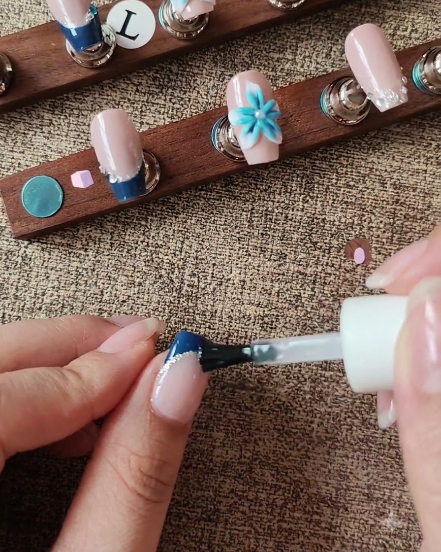 Un pennello che applica il top coat sulla superficie dellunghia evitando un dettaglio floreale 3D.