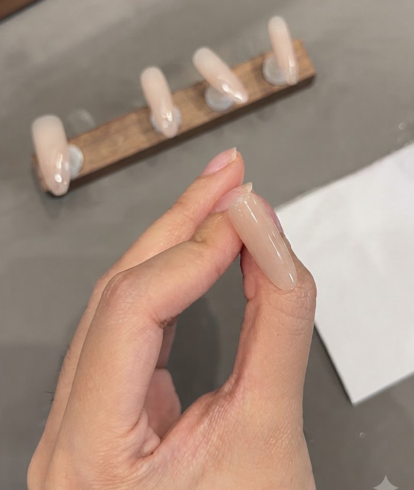 Una vista ravvicinata di ununghia a mandorla che mostra sottili linee bianche precise dipinte vicino alla zona delle cuticole.