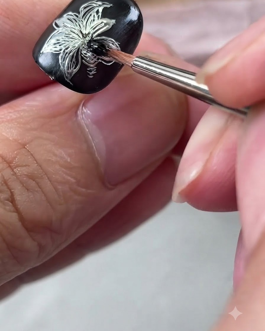 Un pennellino per dettagli che sfuma il gel nero al centro della nail art in argento.