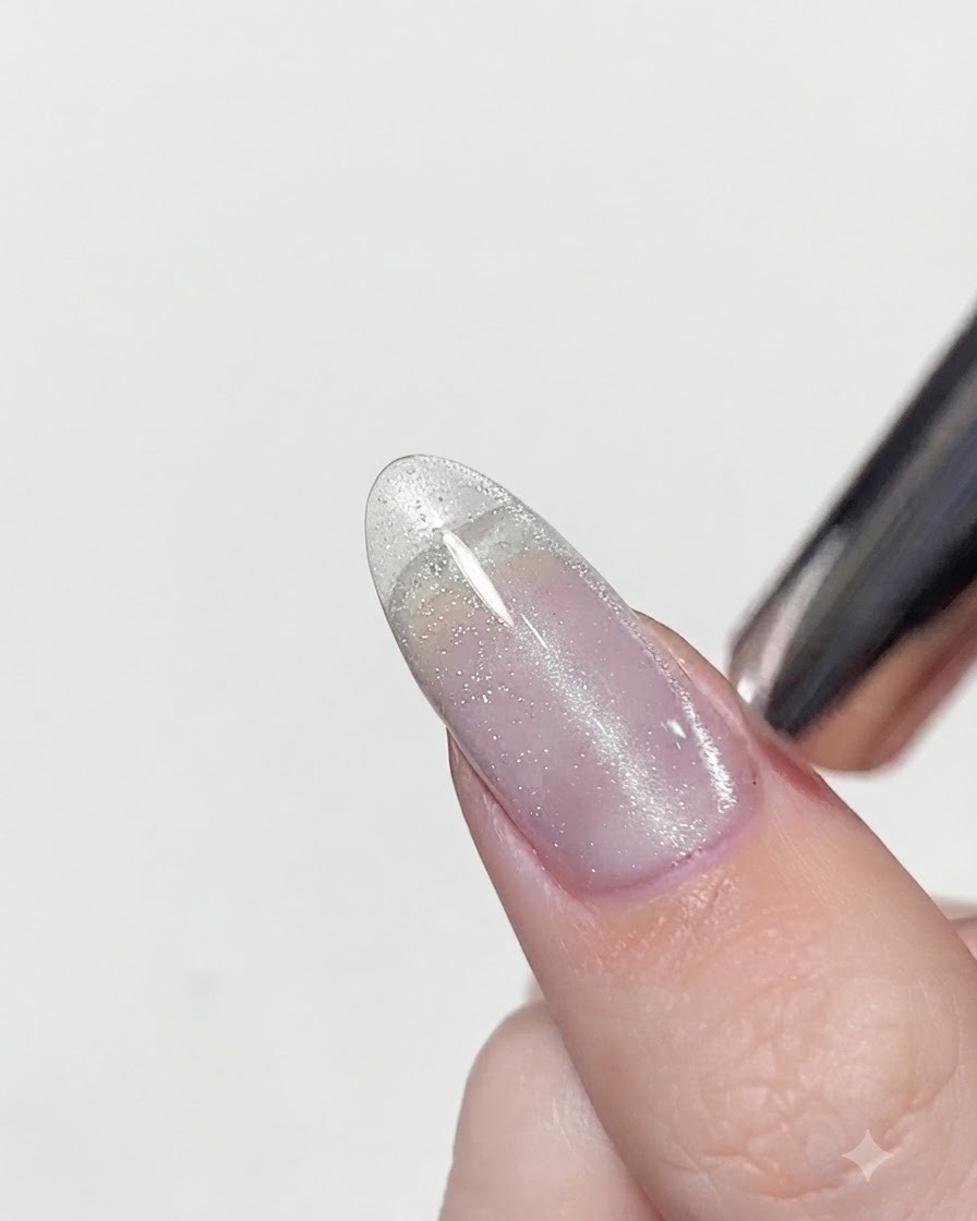 Uno strumento magnetico posizionato molto vicino a ununghia con gel cat eye bagnato per concentrare i riflessi argentati in una linea verticale.