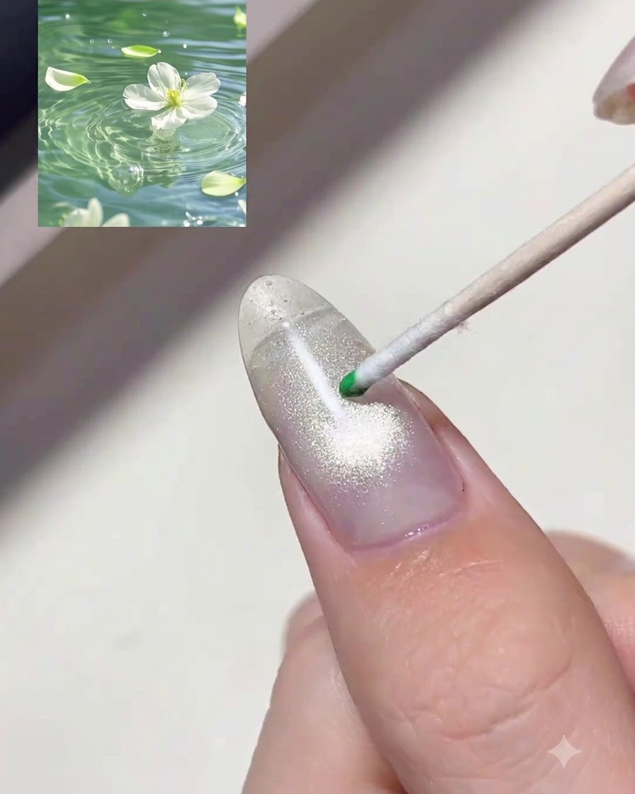Un bastoncino in legno con punta a sfera deposita una goccia di gel tinta verde traslucido su ununghia brillante.