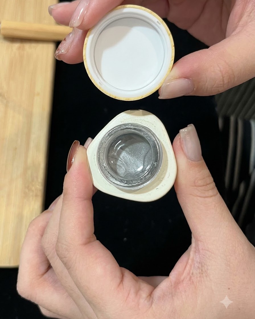 Un piccolo contenitore di gel cat-eye magnetico argento aperto mostra la formula brillante allinterno.