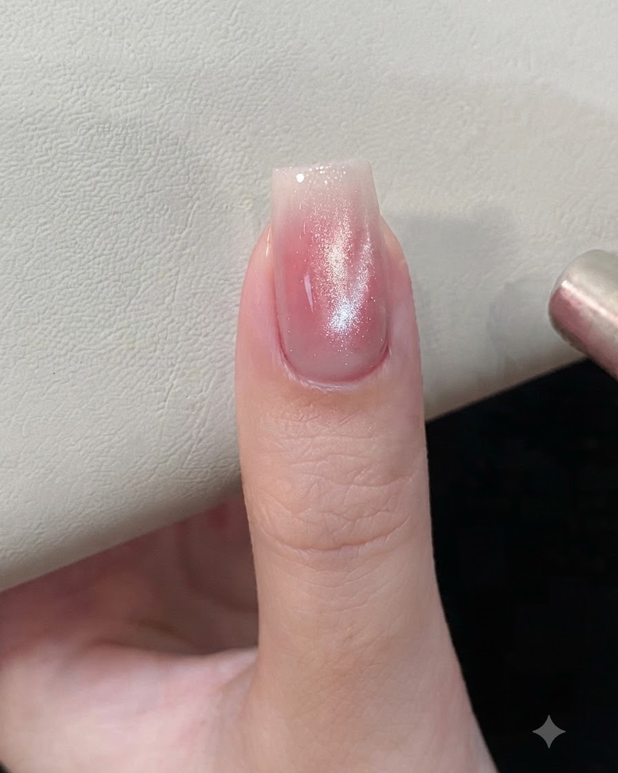 Uno strumento magnetico tenuto vicino a unghie in gel cat-eye rosa e argento per modellare le particelle magnetiche.
