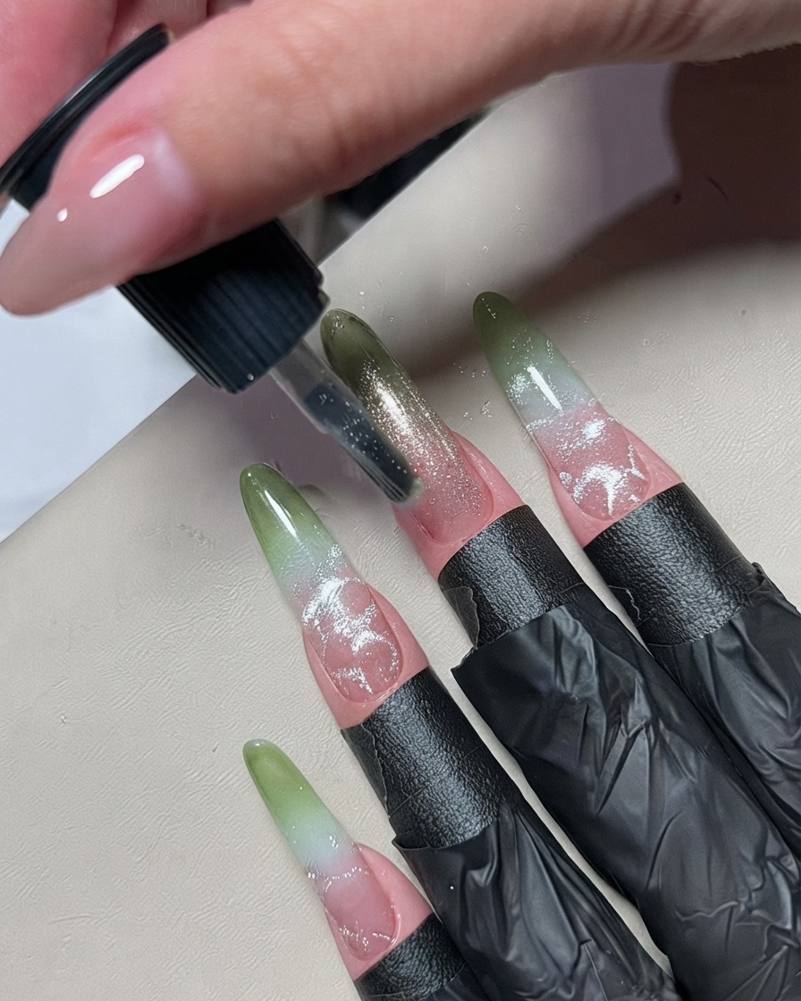 Un piccolo pennello da nail art che applica una sottile linea di smalto gel metallico argentato al centro di ununghia ombré.