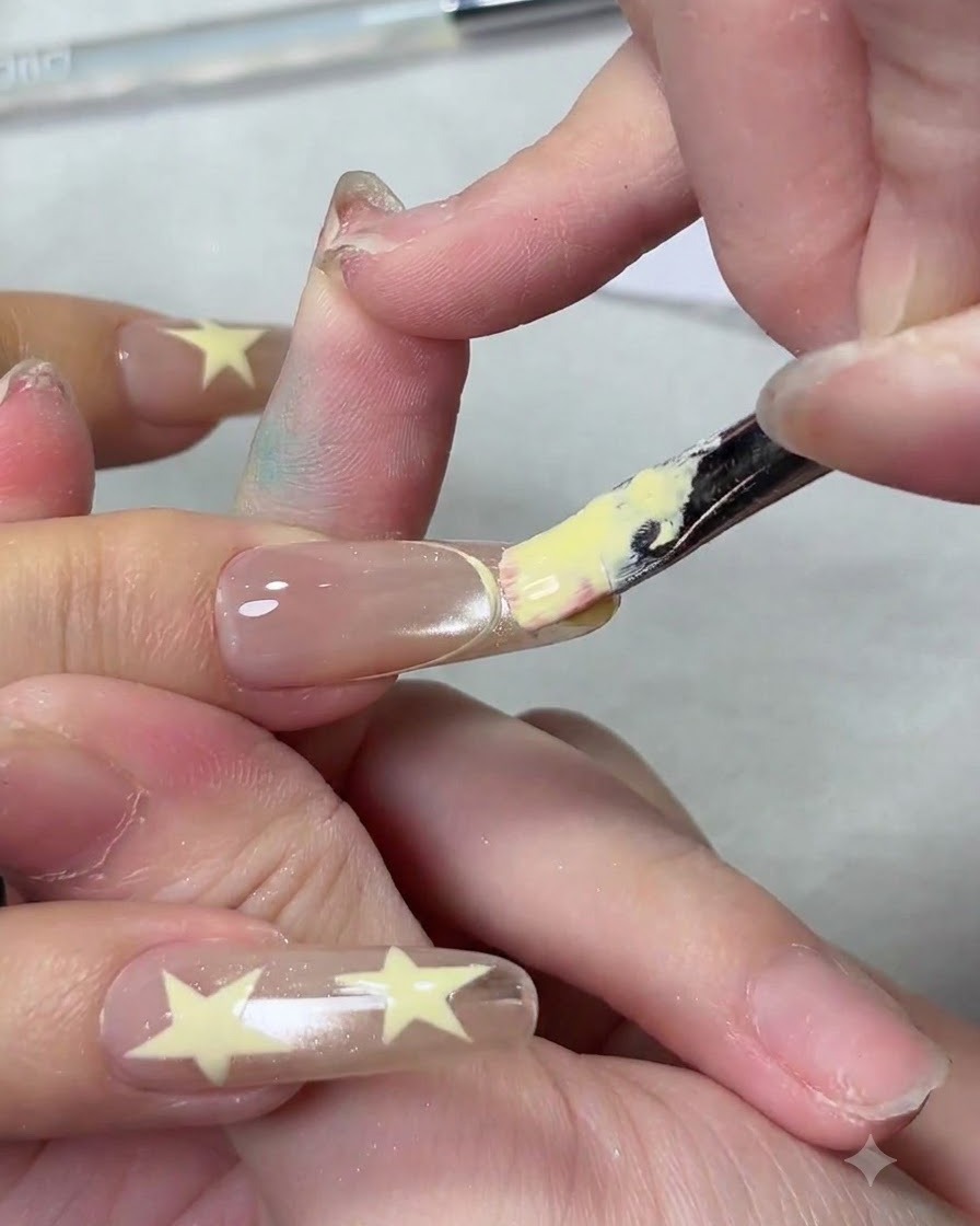 Un pennello piatto per unghie applica uno smalto in gel giallo cremoso sulla punta di ununghia per creare una french manicure.