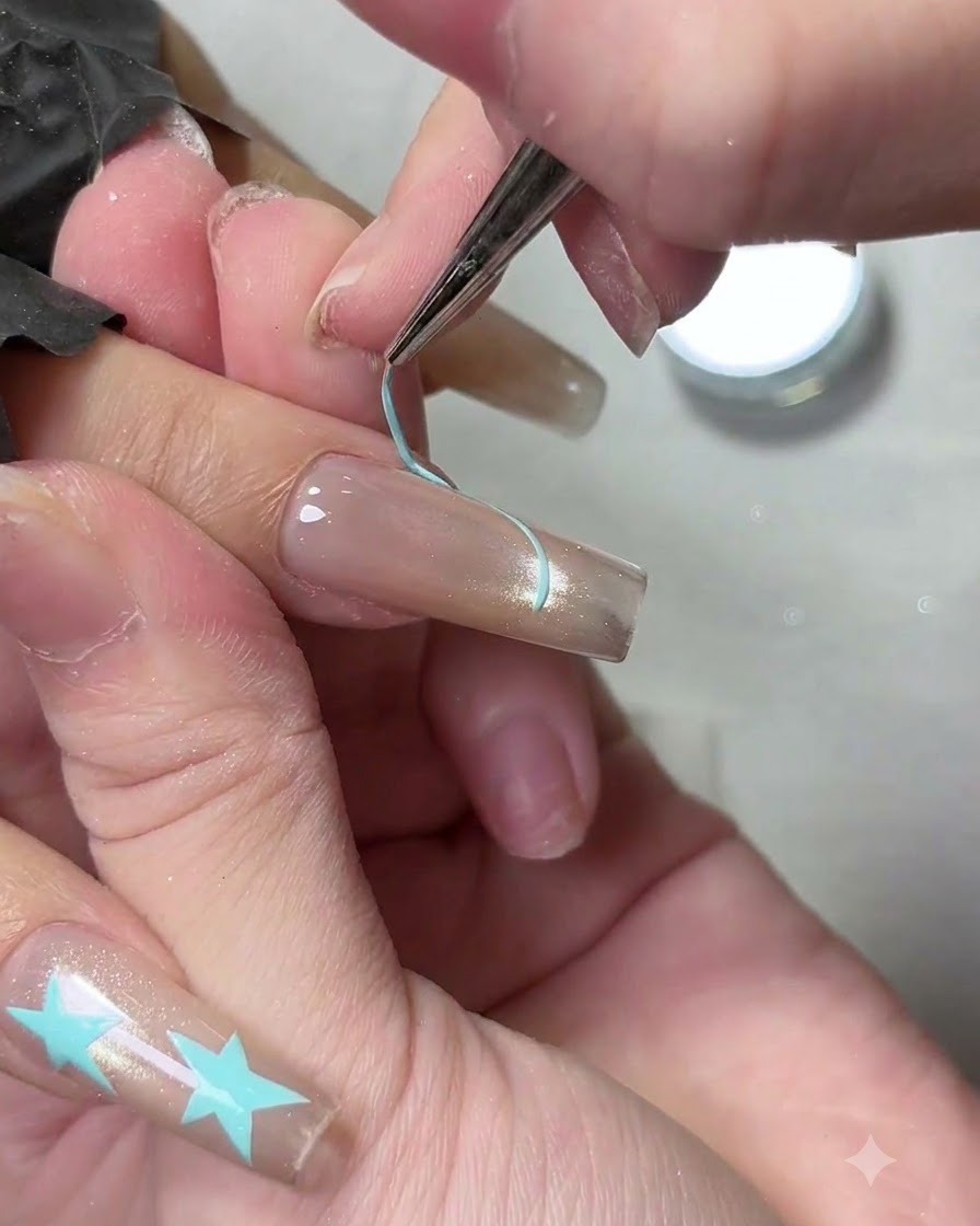 Un pennello liner sottile delinea la linea del sorriso di una french tip azzurra su ununghia curata.