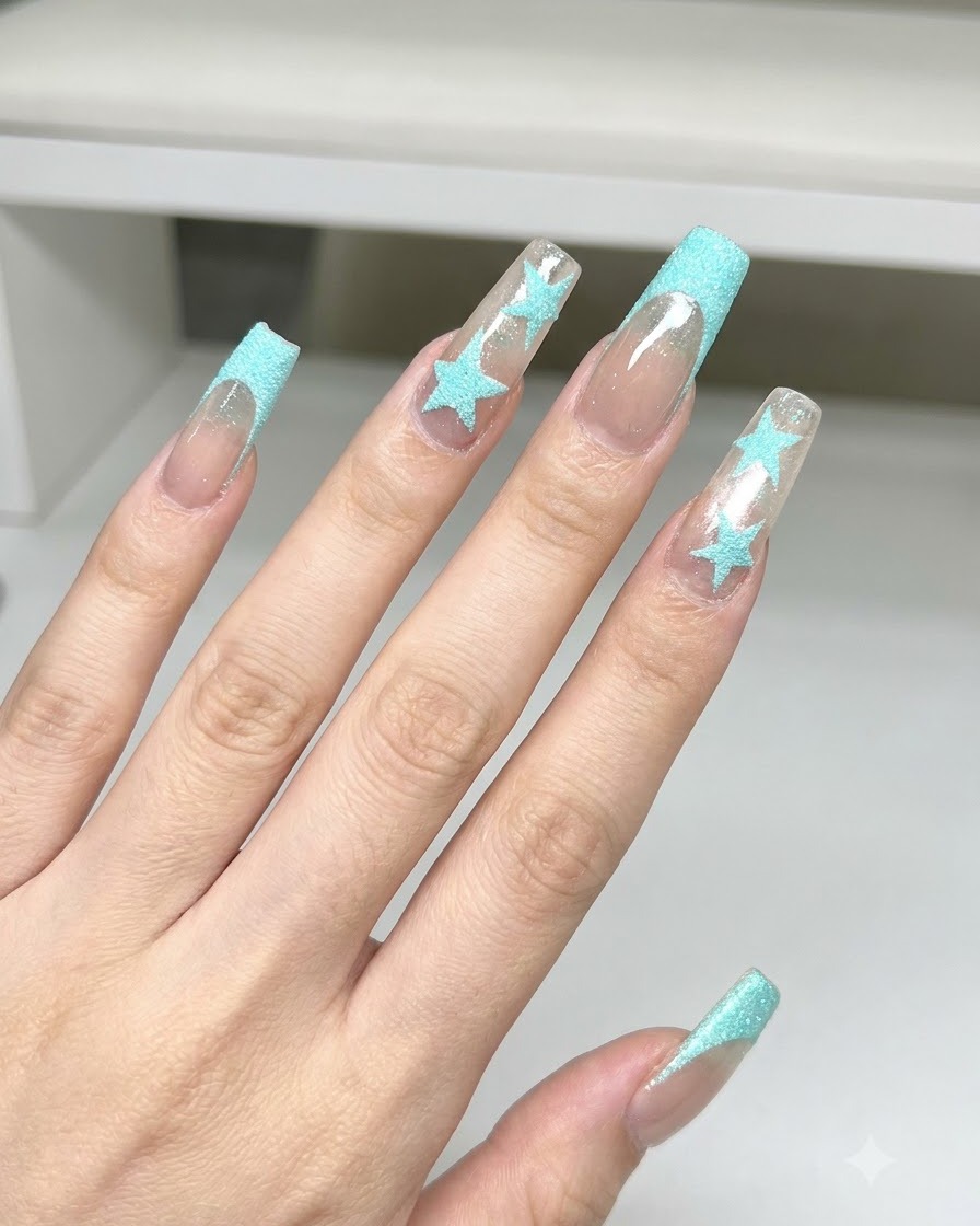 Un pennello da spolvero che pulisce la polvere glitter blu da unghie quadrate lunghe con decorazioni di stelle blu e french tip.